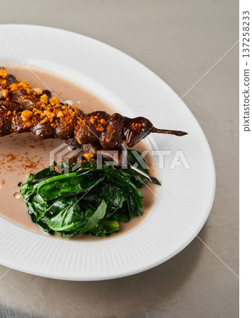 Streetstyle grilled meat served with greens and crunchy nuts 137258233