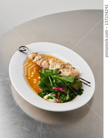 Skewered grilled poultry accented with tangy citrus on fresh greens platter Skewered grilled poultry accented with tangy citrus on fresh greens platter 137258242