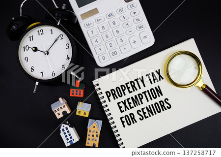 Notepad with the phrase "Property Tax Exemption For Seniors" surrounded by a pen, calculator, magnifying glass, clock, and house model Notepad with the phrase "Property Tax Exemption For Seniors" surrounded by a pen, calculator, magnifying glass, clock, and house model 137258717