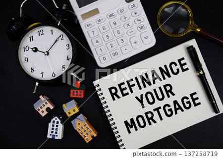 Notepad with the phrase "Refinance Your Mortgage" surrounded by a pen, calculator, magnifying glass, clock, and house model Notepad with the phrase "Refinance Your Mortgage" surrounded by a pen, calculator, magnifying glass, clock, and house model 137258719