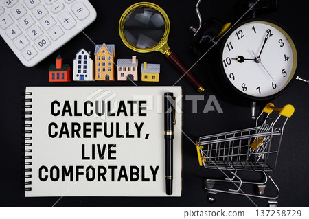 Notepad with the phrase "Calculate Carefully, Live Comfortably" surrounded by a pen, mini trolley shopping cart, magnifying glass, clock, and house model 137258729