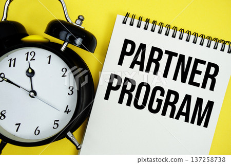 Partner Program text with alarm clock flat lay on yellow background Partner Program text with alarm clock flat lay on yellow background 137258738