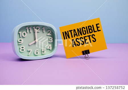 Intangible Assets text and alarm clock on blue and purple background 137258752