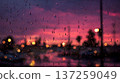 Raindrops cling to glass, blurring a vibrant sunset.  Abstract, moody image with bokeh lights and colorful sky. 137259049