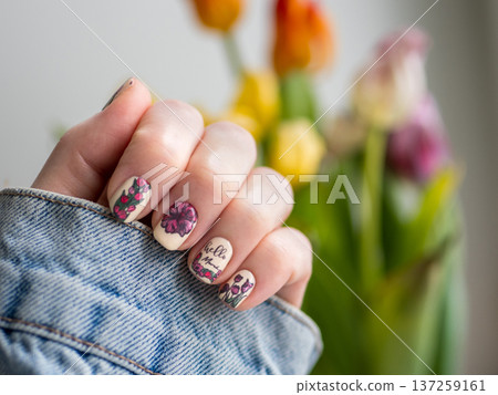 Woman's Hand With Floral Nail Art. Tulips and spring stamping on butter yellow nails. Trendy manicure design and nail art, copy space. 137259161