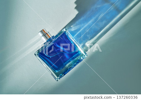 Blue perfume glass bottle with sunlight reflections on surface 137260336