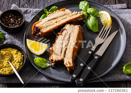 Roasted pork belly ribs with pesto and lemon 137260361