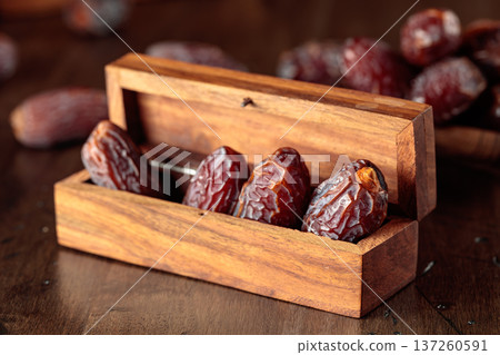 Dates fruits in small wooden box on an old wooden table. Dates fruits in small wooden box on an old wooden table. 137260591