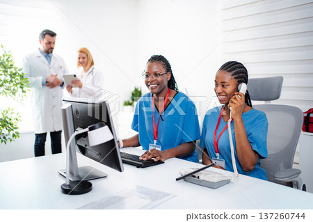 Nurses working on computer and talking on phone in medical office 137260744