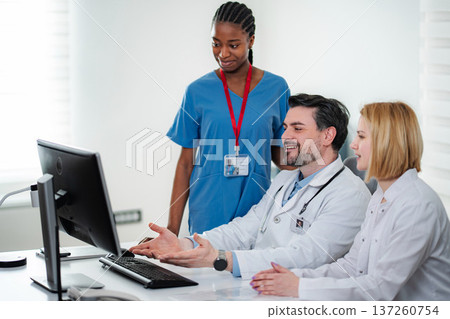 Medical team collaborating on computer in clinic office Medical team collaborating on computer in clinic office 137260754
