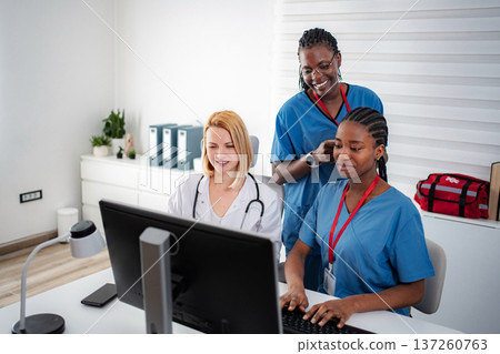 Healthcare professionals collaborating on computer in medical office 137260763