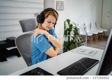 Female professional feeling shoulder pain while working at desk 137260802