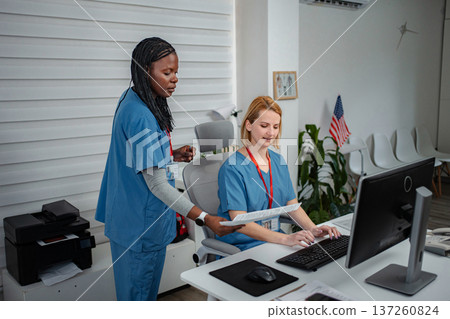 Diverse medical staff collaborating on patient documentation at clinic 137260824