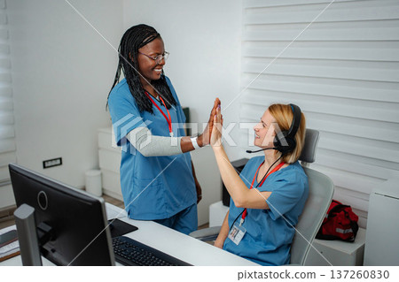Diverse medical professionals celebrating teamwork and success with a high five Diverse medical professionals celebrating teamwork and success with a high five 137260830