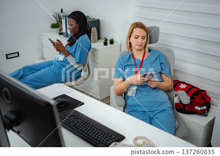 Nurses scrolling on smartphones ignoring work in office Nurses scrolling on smartphones ignoring work in office 137260835