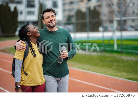 Diverse couple laughing hugging after running training Diverse couple laughing hugging after running training 137260970