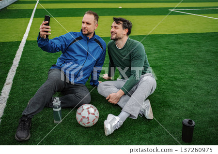 Two men taking selfie on soccer field, enjoying friendship Two men taking selfie on soccer field, enjoying friendship 137260975