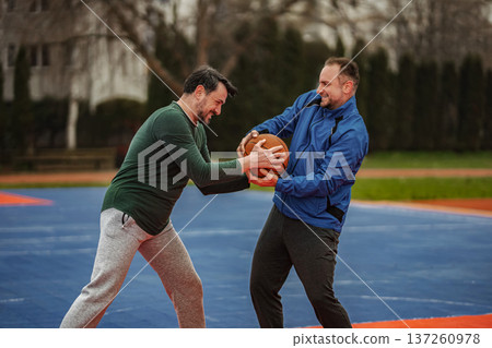Two men competing for basketball on outdoor court 137260978