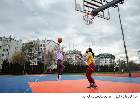 Women playing basketball outdoors on urban court Women playing basketball outdoors on urban court 137260979