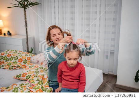 Mother styling daughter's hair with comb in bedroom Mother styling daughter's hair with comb in bedroom 137260981