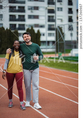 Diverse couple smiling on running track, enjoying fitness together 137260987