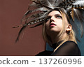 Young woman wearing elaborate feather headdress looking up 137260996