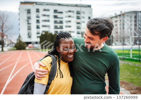 Interracial couple hugging and laughing on outdoor track 137260999