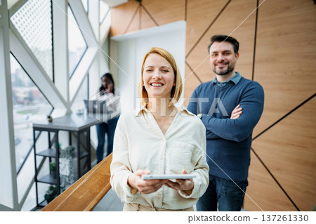 Business partners smiling with tablet in modern office Business partners smiling with tablet in modern office 137261330