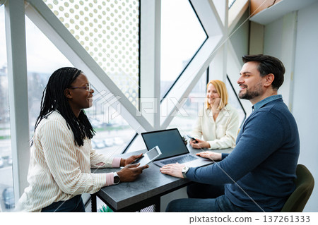 Diverse business team collaborating during a casual meeting Diverse business team collaborating during a casual meeting 137261333
