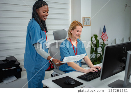 Medical professionals collaborating on documents at clinic front desk 137261381