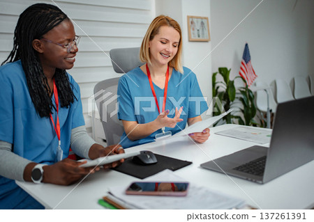 Diverse nurses collaborating on medical records in clinic office Diverse nurses collaborating on medical records in clinic office 137261391