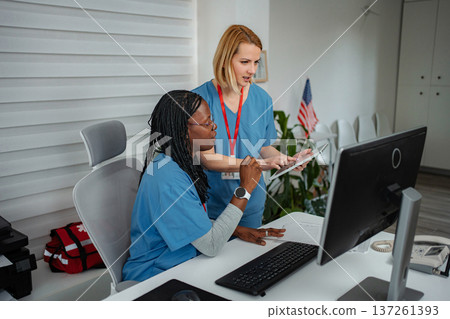Healthcare professionals collaborating on computer and digital tablet in a clinic Healthcare professionals collaborating on computer and digital tablet in a clinic 137261393