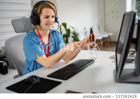 Nurse wearing headset doing telemedicine consultation showing medication 137261428