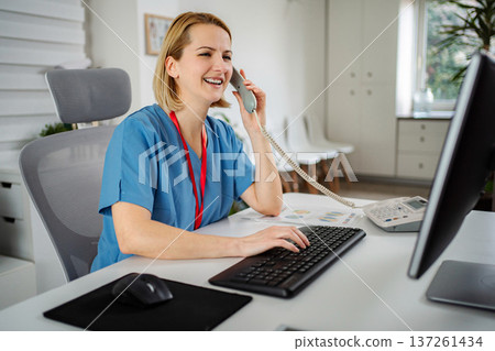 Healthcare professional smiling talking on telephone working at clinic 137261434