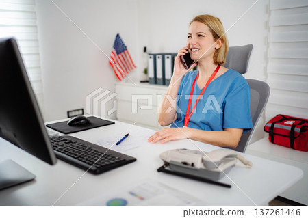 Healthcare professional talking on phone at desk with American flag 137261446