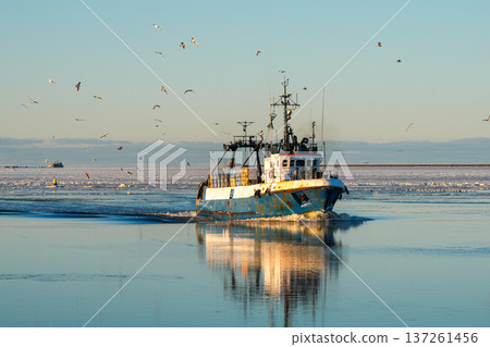 Fishing Vessel Returning to Liepaja Port on Icy Baltic Sea at Sunset Fishing Vessel Returning to Liepaja Port on Icy Baltic Sea at Sunset 137261456