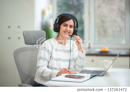 Young woman working from home using headset for remote call 137261472