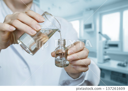 Pouring liquid into a vial Pouring liquid into a vial 137261609