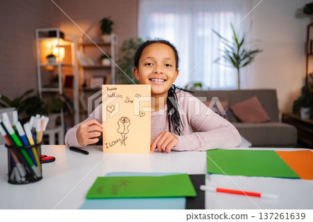 Girl holding handmade Mother's Day card smiling Girl holding handmade Mother's Day card smiling 137261639