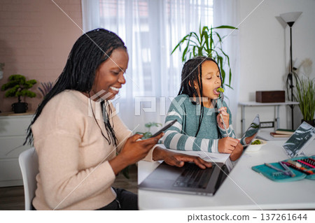Mother and daughter multitasking working and studying at home 137261644