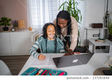 Mother and daughter remote learning at home with laptop Mother and daughter remote learning at home with laptop 137261649