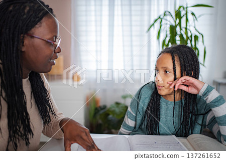 Mother tutoring daughter at home, helping with school homework 137261652