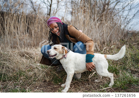Joyful young adult woman with dog in field Joyful young adult woman with dog in field 137261656