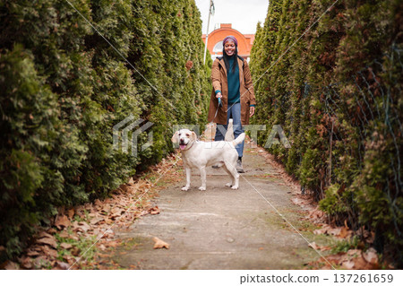 Happy young woman walking with dog on leash outdoors Happy young woman walking with dog on leash outdoors 137261659