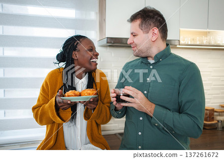 Smiling diverse couple enjoying morning coffee and breakfast Smiling diverse couple enjoying morning coffee and breakfast 137261672