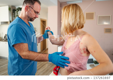 Doctor examining female patient with rash during home visit Doctor examining female patient with rash during home visit 137261697