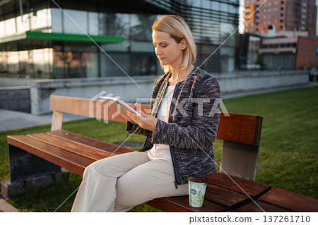 Businesswoman working on tablet outdoors enjoying coffee break Businesswoman working on tablet outdoors enjoying coffee break 137261710