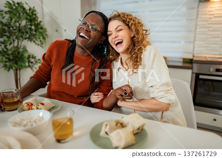 Happy diverse women laughing enjoying lunch together in kitchen 137261729