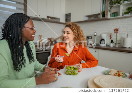 Two Women Friends Enjoying Healthy Breakfast and Conversation in Kitchen Two Women Friends Enjoying Healthy Breakfast and Conversation in Kitchen 137261732