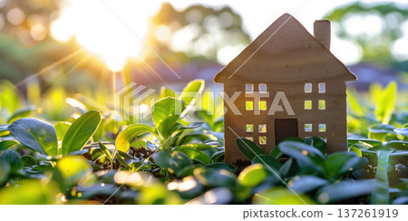Sunlight shines on a small house model amidst vibrant green plants in a peaceful garden Sunlight shines on a small house model amidst vibrant green plants in a peaceful garden 137261919